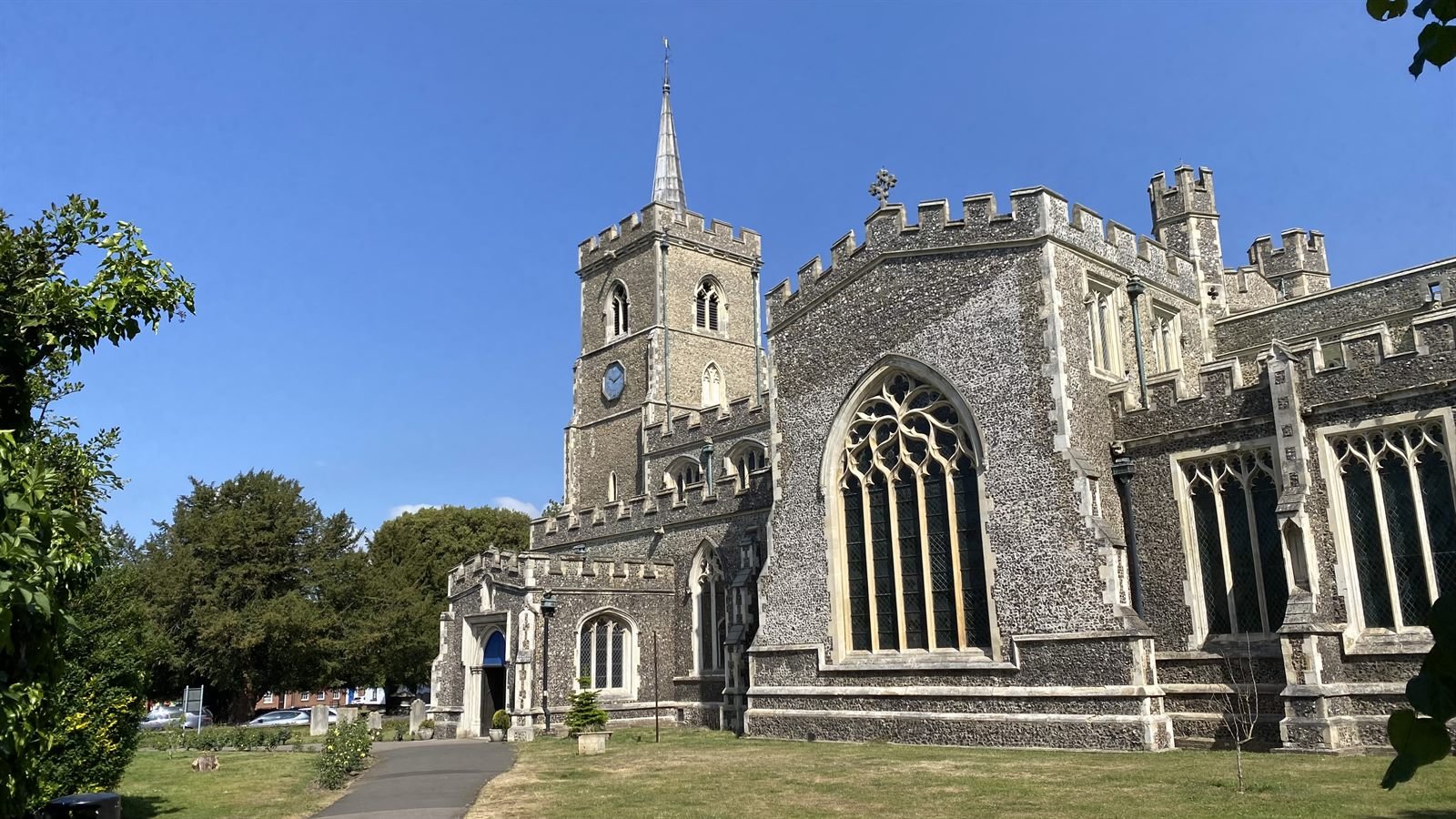 The flint tower and spire of St Mary the Virgin, Ware, against a blue summer sky